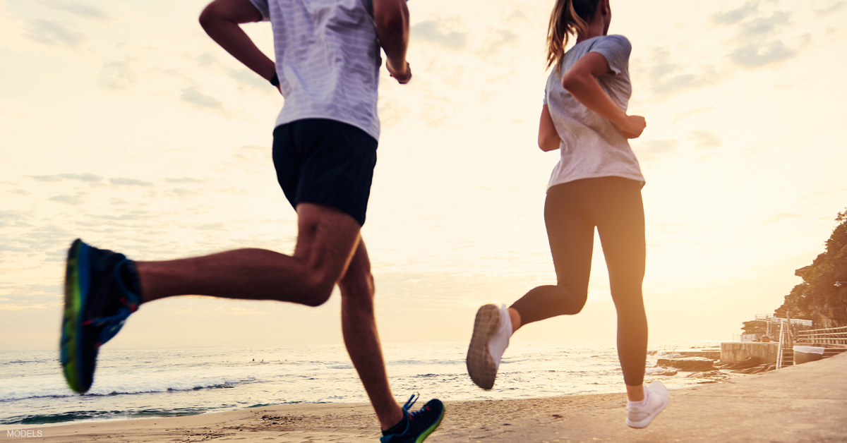 man and woman jogging on the beach