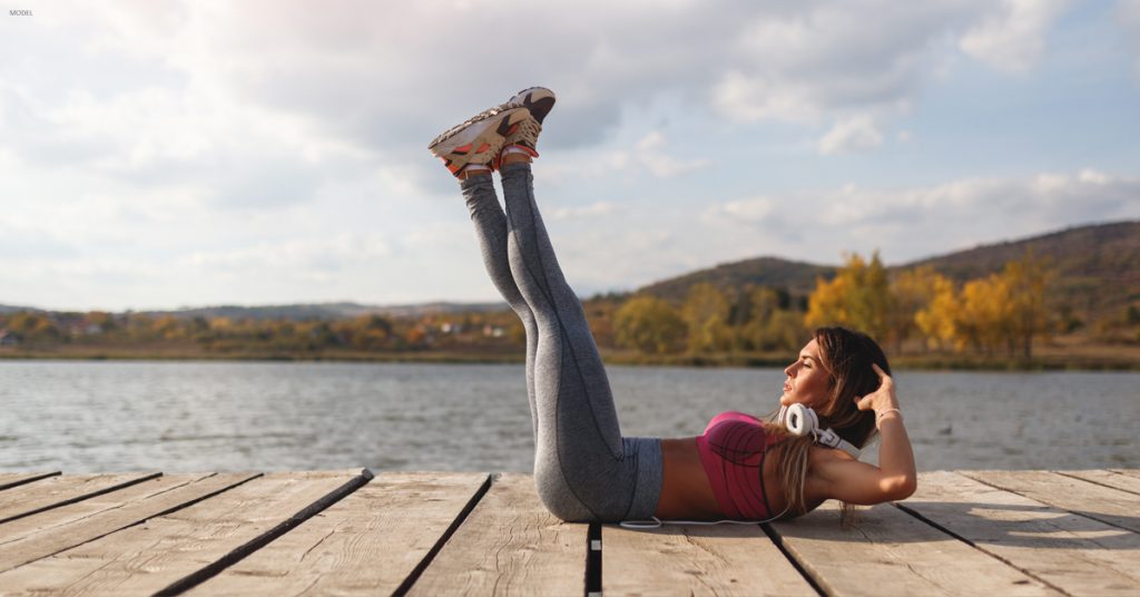 Woman on dock next to lake doing crunches