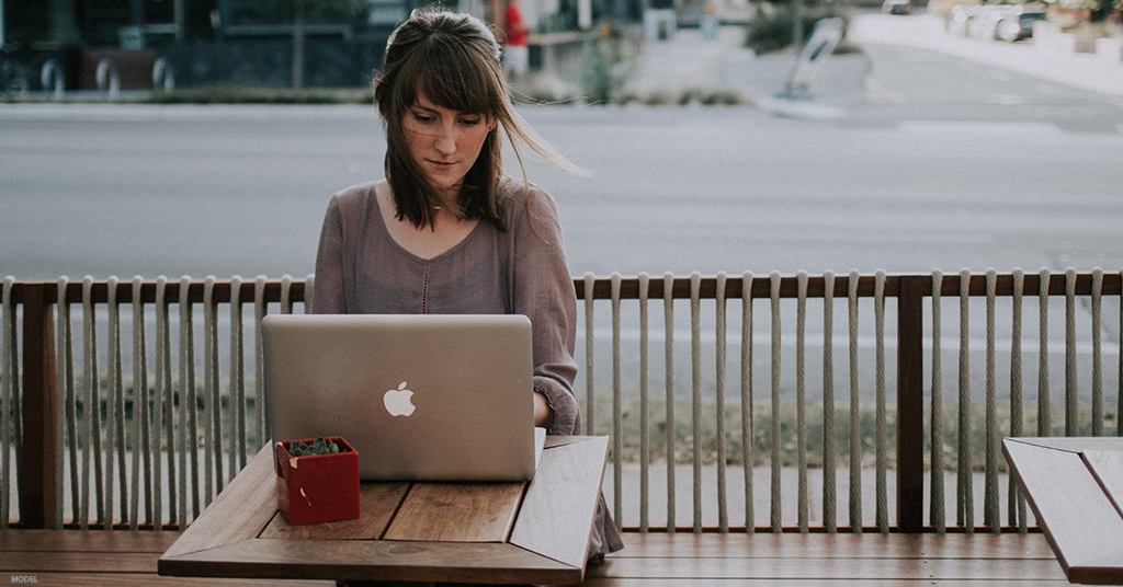 A woman looks through before and after photos on her laptop.