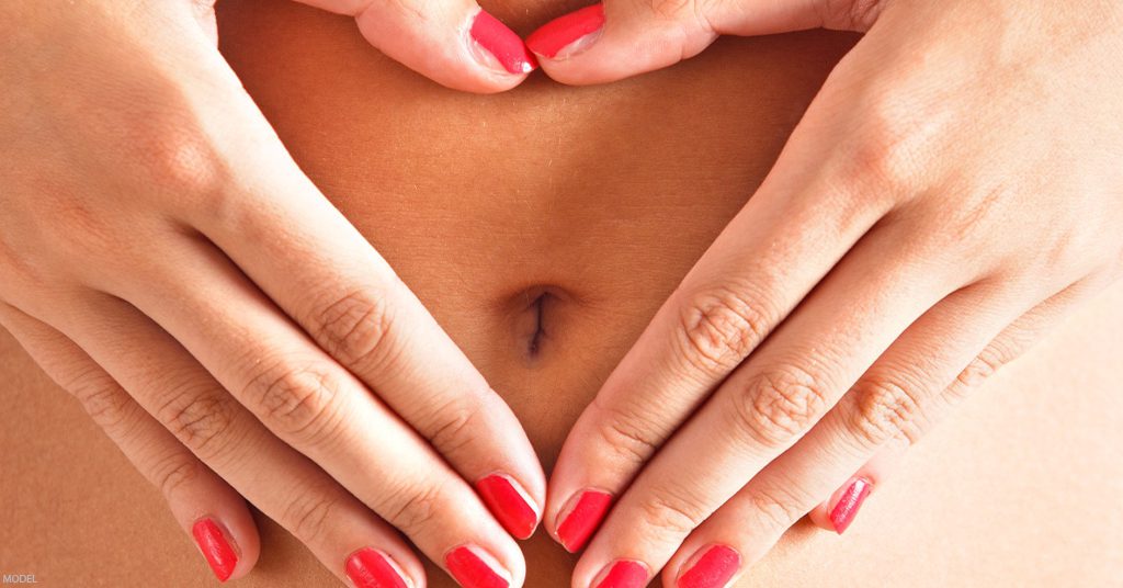 A woman touches her stomach after receiving a tummy tuck.